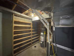 Utility room featuring water heater and heating unit with shelving.