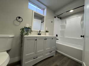 Full bathroom featuring vanity, bathing tub / shower combination, upgraded toilet and dark wood-type flooring.