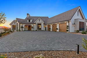 View of front of home featuring a chimney, decorative driveway, brick siding, and a garage