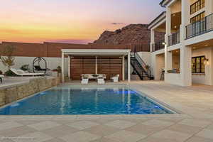 Pool at dusk with a patio, outdoor lounge area, and an outdoor pool
