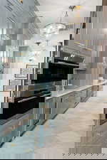 Bar with stainless steel double oven, hanging lights, beverage cooler, and light stone counters