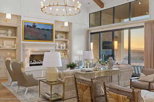 Living area featuring built in shelves, a fireplace with raised hearth, wood finished floors, and a chandelier