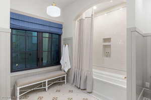 Bathroom with shower / tub combo and wainscoting