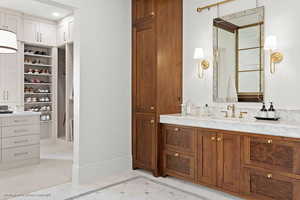 Full bath featuring vanity, inlaid floor details, and a spacious closet