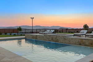 Pool at dusk with a patio area and a mountain view