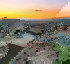 View of front facade featuring a chimney, a porch, and concrete driveway