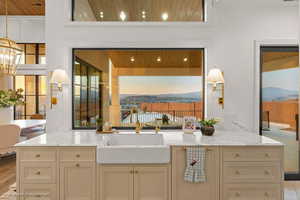 Kitchen featuring cream cabinetry, light stone counters, wood ceiling, and suspended lighting