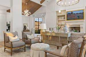 Living area with suspended lighting, built in features, a high wooden beamed ceiling, wood finished floors, and a fireplace