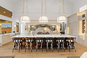 Kitchen featuring decorative light fixtures, light stone counters, a breakfast bar, vaulted ceiling, and a decorative wall
