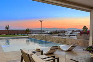 Pool at dusk featuring a fenced backyard, a patio area, a mountain view, and an outdoor pool