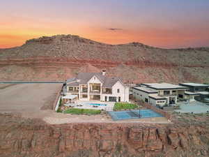 Back of house at dusk featuring a patio area, an outdoor pool, a mountain view, and a chimney