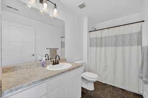 Bathroom featuring a shower with shower curtain, vanity, and dark tile patterned flooring