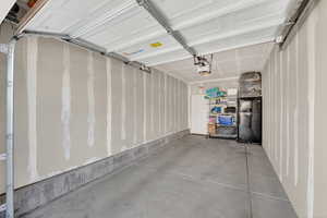 Garage featuring freestanding refrigerator and a garage door opener