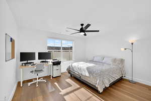 Bedroom featuring wood finished floors, a ceiling fan, and an office area