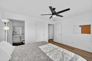 Bedroom featuring dark wood-type flooring, ensuite bathroom, and ceiling fan