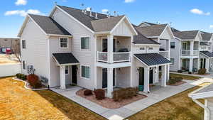 Back of house featuring a balcony, a yard, roof with shingles, and a residential view