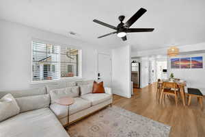 Living room with light wood-type flooring, a ceiling fan, and a textured ceiling
