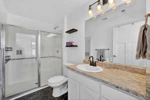 Bathroom with a shower stall, vanity, and dark tile patterned floors