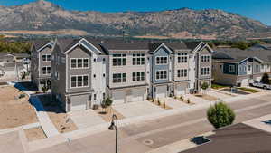 View of front of property with a mountain view, concrete driveway, a garage, and a residential view