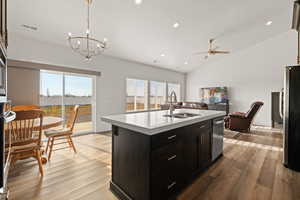 Eat-in kitchen and semi formal dining area featuring a spacious island with quartz countertops, LVP flooring, vaulted ceilings, and a sliding patio door