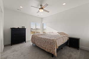 Primary bedroom featuring carpeted floors, ceiling fan, and natural light