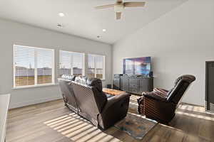 Open concept living area featuring LVP flooring, vaulted ceilings, and natural light