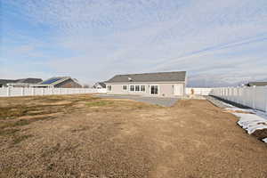 Back of property with a patio area, some xeriscape landscaping, and full vinyl fence