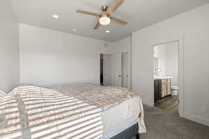 Primary bedroom featuring carpeted floors, ceiling fan, and natural light with attached en-suite bathroom
