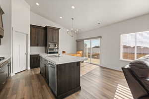 Open concept gourmet kitchen featuring dark wood cabinetry, quartz countertops, vaulted ceilings, and a semi-formal dining area
