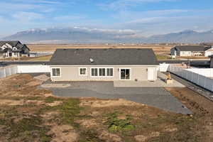 Rear view of property with a patio area, a fenced backyard, a mountain view, and a shingled roof