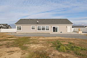 Back of property with a patio area, some xeriscape landscaping, and full vinyl fence