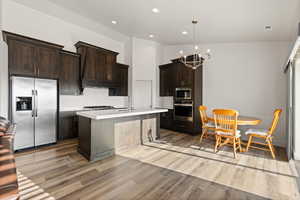 Open concept gourmet kitchen featuring dark wood cabinetry, quartz countertops, vaulted ceilings, and a semi-formal dining area