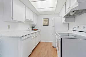 Kitchen has been updated with new countertops, white cabinetry, and new light fixtures.