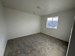 Carpeted empty room featuring baseboards and a textured ceiling