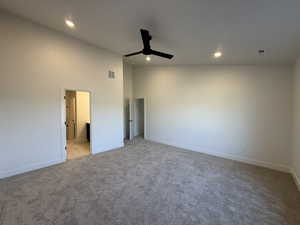 Unfurnished bedroom featuring light carpet, ceiling fan, recessed lighting, ensuite bath, and vaulted ceiling