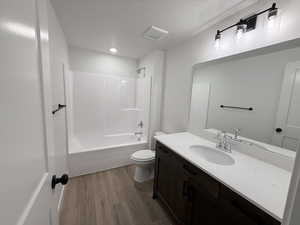 Full bathroom featuring vanity, dark wood-style flooring, shower / tub combination, and a textured ceiling