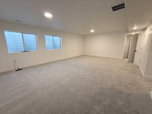 Empty room with light carpet and recessed lighting