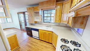 Kitchen with light wood finished floors, light countertops, white appliances, and healthy amount of natural light
