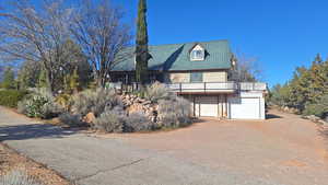 View of front of property with driveway, a garage, a metal roof, and a wooden deck