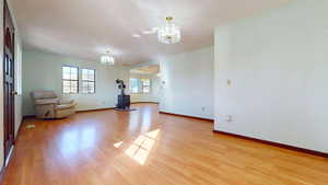 Unfurnished living room featuring a wood stove, a chandelier, and light wood-type flooring