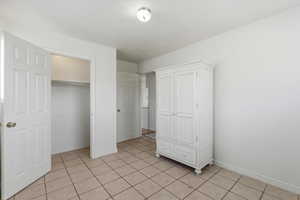 Unfurnished bedroom with a closet and light tile patterned floors