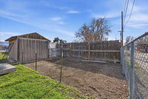 Fenced backyard featuring a storage unit