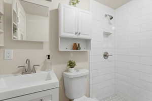 Bathroom featuring tiled shower and vanity
