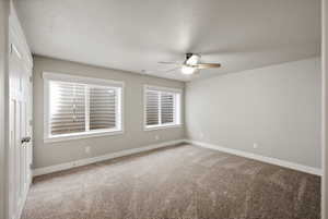 Empty room featuring light colored carpet, a textured ceiling, and a ceiling fan
