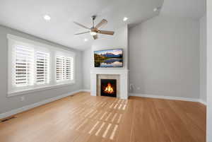 Unfurnished living room with lofted ceiling, light wood-style floors, a ceiling fan, a tiled fireplace, and recessed lighting