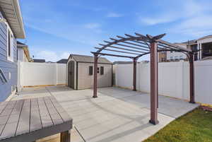 Fenced backyard featuring a storage unit, a patio area, and a pergola