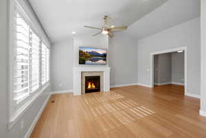 Unfurnished living room featuring ceiling fan, a fireplace, light wood-style flooring, and lofted ceiling