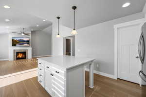 Kitchen featuring hanging light fixtures, a tile fireplace, dark wood finished floors, a center island, and lofted ceiling