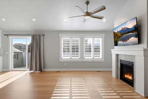 Unfurnished living room featuring a tile fireplace, ceiling fan, light wood-type flooring, and recessed lighting