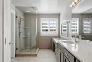 Bathroom featuring a stall shower, vanity, tile walls, and light tile patterned floors